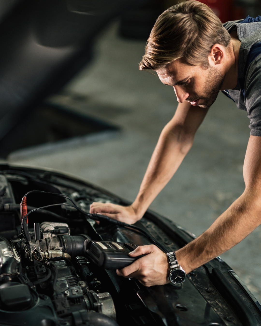 Kfz-Mechaniker prüft mit einem Diagnosegerät den Motor eines Autos
